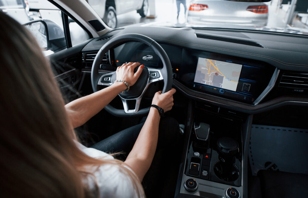 Using GPS. Girl in modern car in the salon. At daytime indoors. Buying new vehicle.